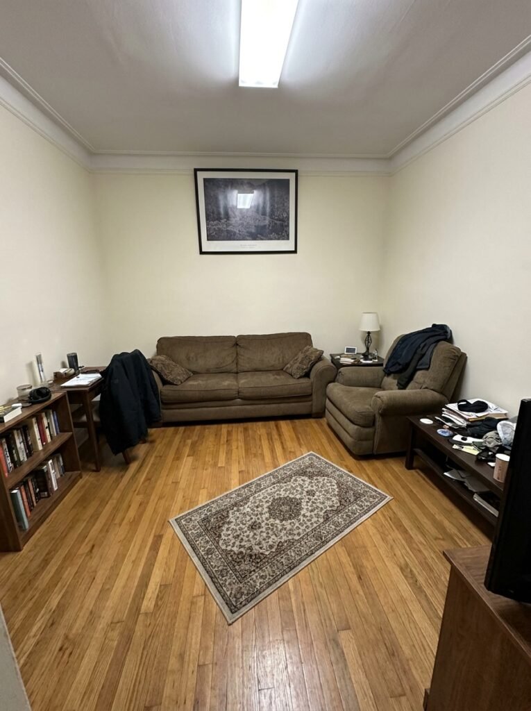Small living room with all furniture pushed against the walls and an undersized center rug