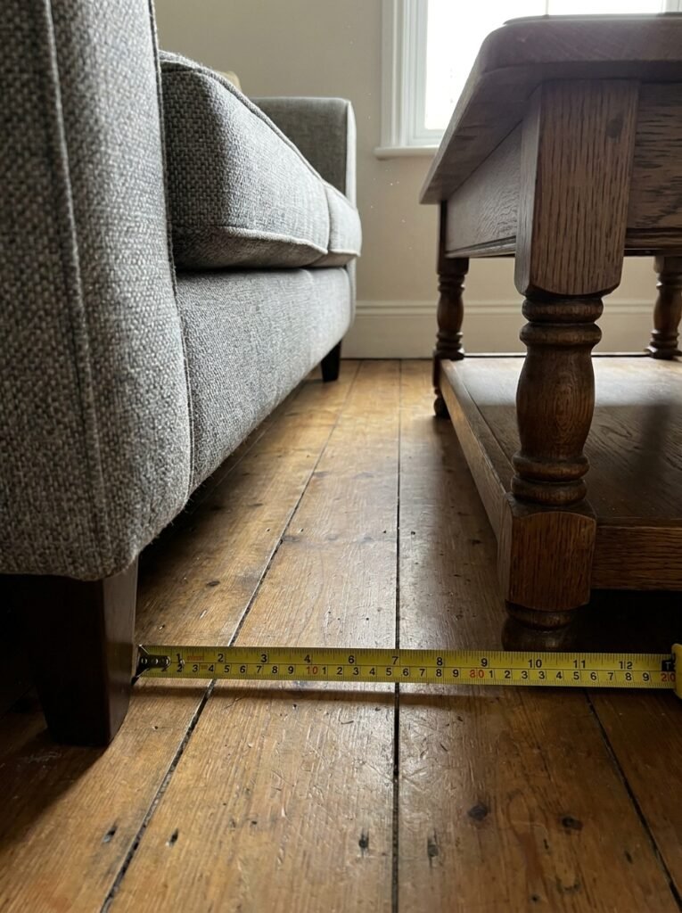 Tape measure showing the spacing between a sofa and coffee table in a small living room
